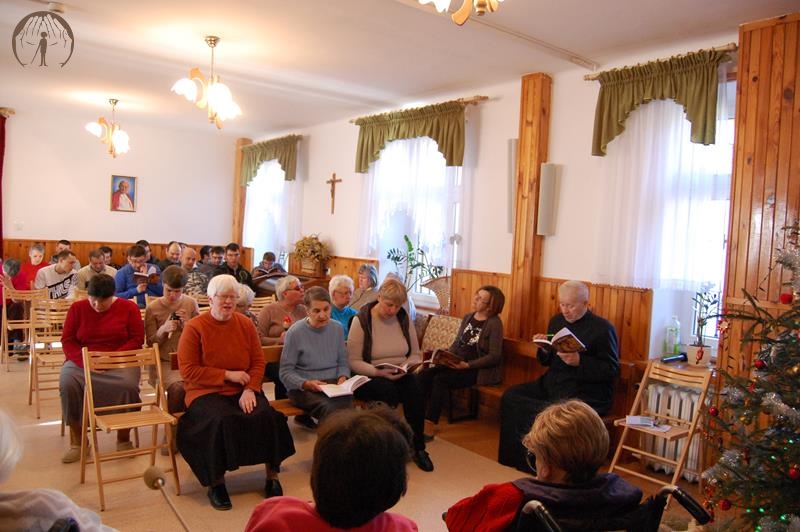 Świetlica w Domu Nadziei, Kolędnicy siedzą na krzesłach w kilku rzędach i śpiewają kolędy 