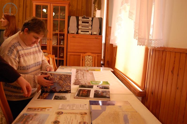 Świetlica w Domu Nadziei, pani Grażynka stoi przy stole z pamiątkami i  ogląda album o Ziemi Świętej