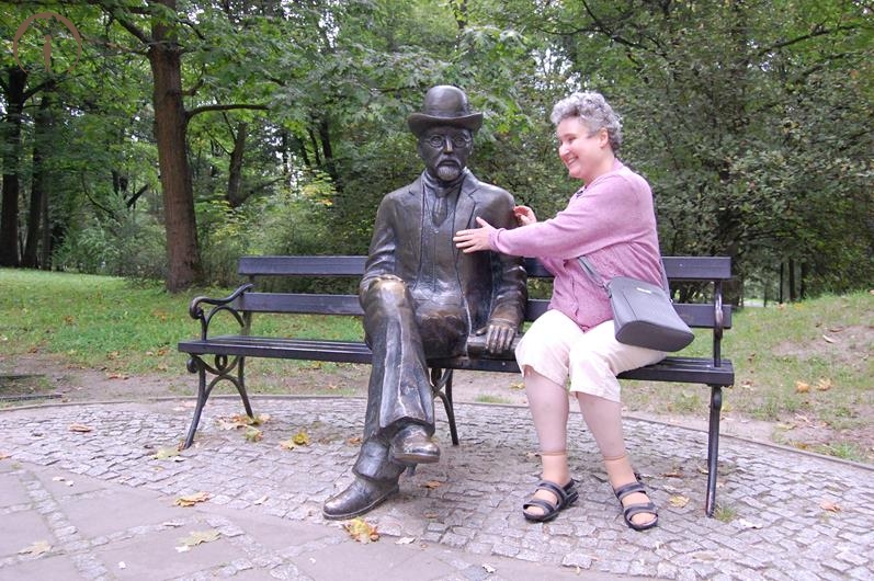 Nałęczów, Park Zdrojowy, Pani Dagmara siedzi na ławeczce i ogląda figurę Bolesława Prusa, również siedzącej na ławeczce, naturalnej wielkości odlanej z brązu