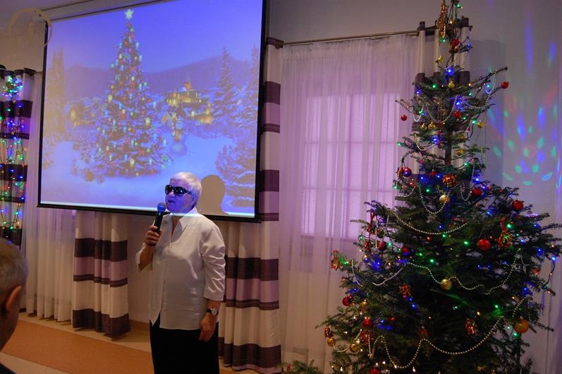Sala muzykoterapii, pani Maria zwraca się do Zgromadzonych, na ekranie wyświetlony obraz świątecznej choinki
