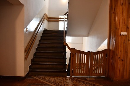 Klatka schodowa na parterze budynku Dom Nadziei, schody w górę, wahadłowe drzwi przed schodami w dół