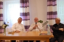 Przy prezydialnym stole siedzą uśmiechnięty ks. Mirosław, radośnie mówiący ks. Grzegorz i uśmiechnięty ks. Antoni