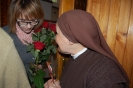 Hol przed kaplicą, Pani Katarzyna pomaga mieszkance wręczyć różę Siostrze Elizie.