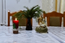 Ołtarzyk kolędowy, figurka Matki Bożej z Dzieciątkiem Jezus na rękach w towarzystwie św. Józefa, zapalona świeca, stroik z świerkowych gałązek
