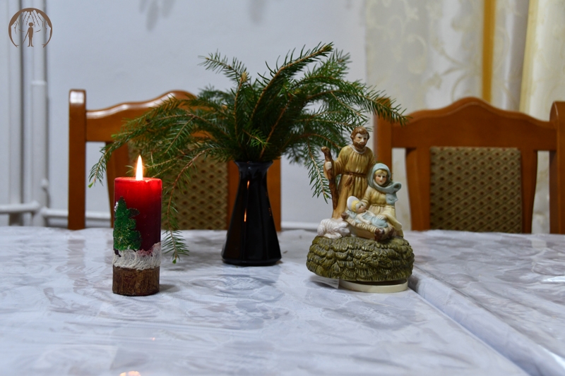 Ołtarzyk kolędowy, figurka Matki Bożej z Dzieciątkiem Jezus na rękach w towarzystwie św. Józefa, zapalona świeca, stroik z świerkowych gałązek