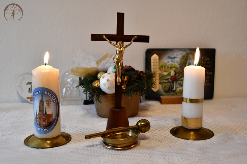 Ołtarzyk kolędowy, krucyfiks, zapalone świece, stroik świąteczny