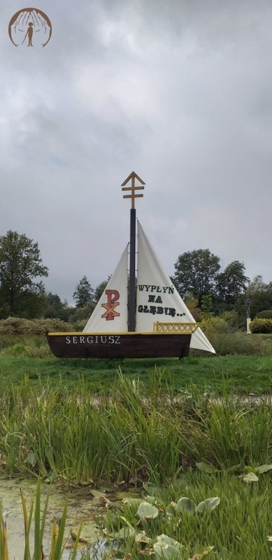 Przyklasztorne ogrody Misjonarzy Oblatów, łódka nad brzegiem stawu z napisem na żaglu 