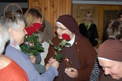 Hol przed kaplicą, Pani Katarzyna pomaga Pani Stanisławie wręczyć różę Siostrze Rufinie